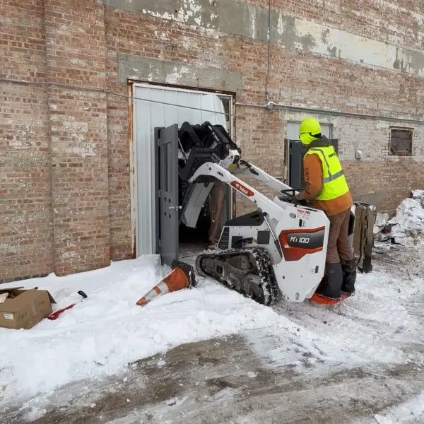 HammerCore Group worker operating Bobcat skid steer during commercial demolition project.
