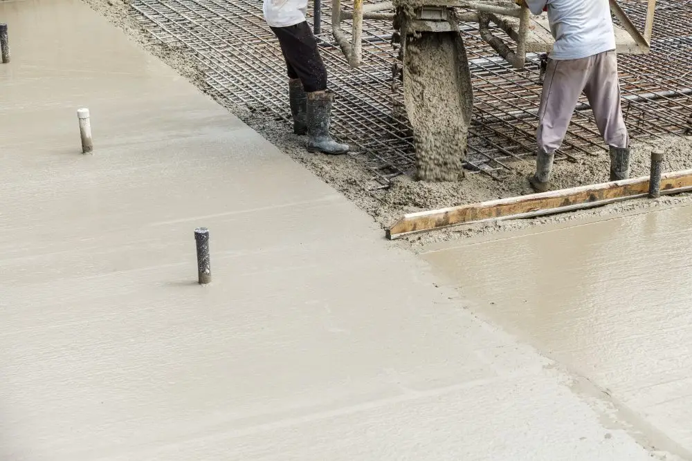 Construction workers pouring concrete for foundation work and site preparation.