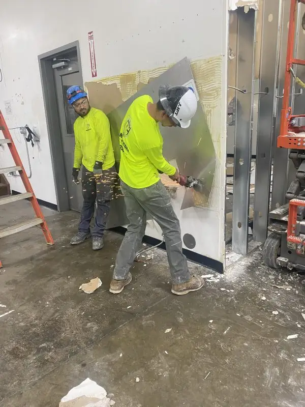 Commercial interior demolition with workers removing drywall and preparing for remodeling.