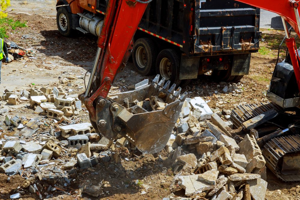 Hydraulic excavator demolishing structure and removing concrete debris in Iowa.