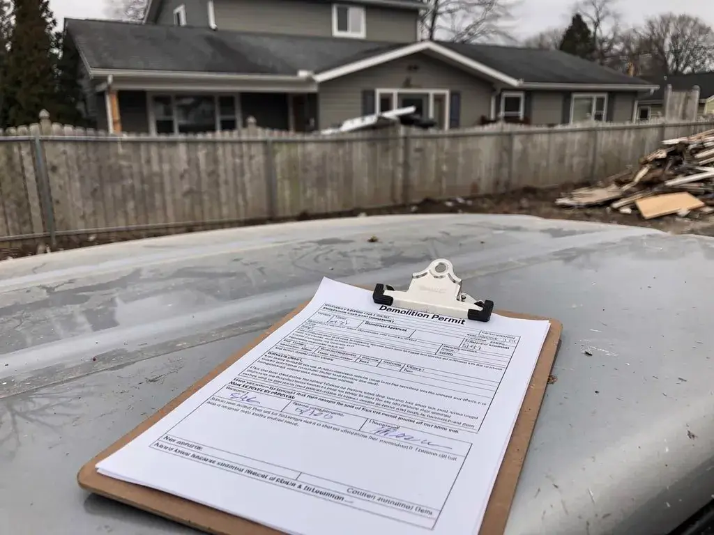 Demolition permit and paperwork on clipboard illustrating house demolition planning process.