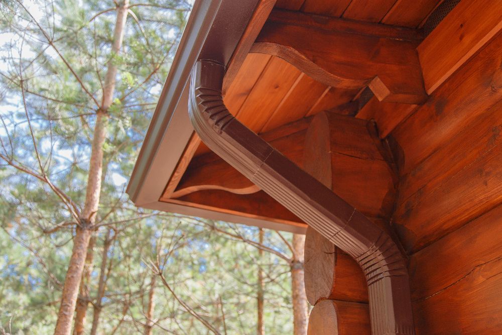Brown gutter and downspout on the exterior of a wood-sided home